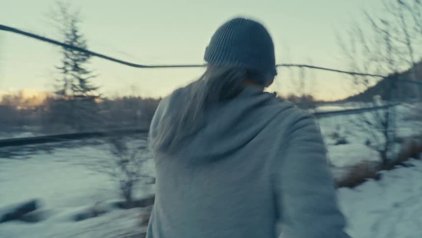 A man runs alongside some train tracks in the snow