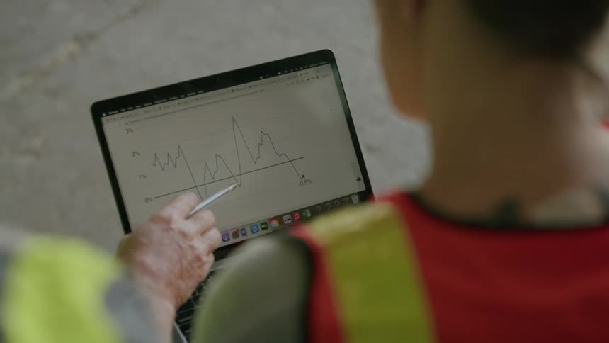 A man and woman talk while looking at a diagram on the laptop