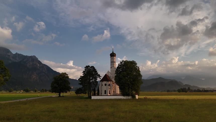 A shot of a remote church with a minaret the camera zooms in between two trees