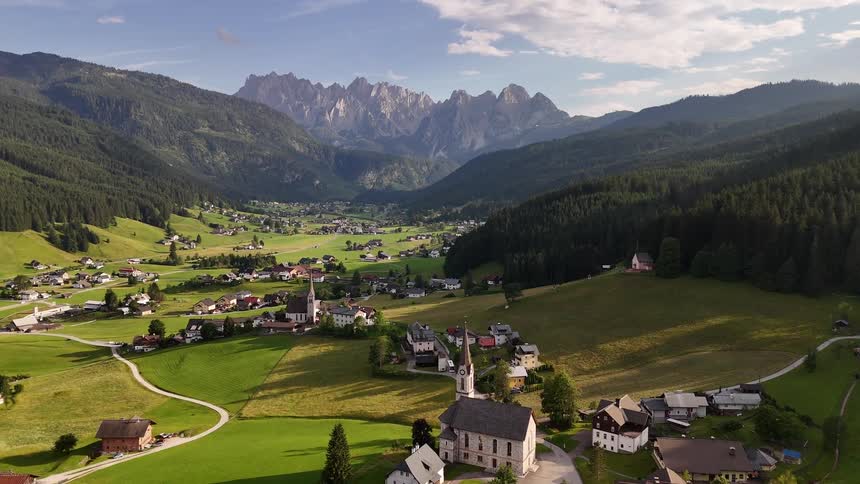 Village nestled in the valley between mountains under a blue sky