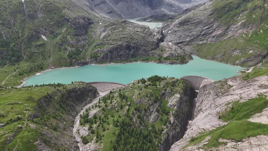 A turquoise lake surrounded by mountains and two dams
