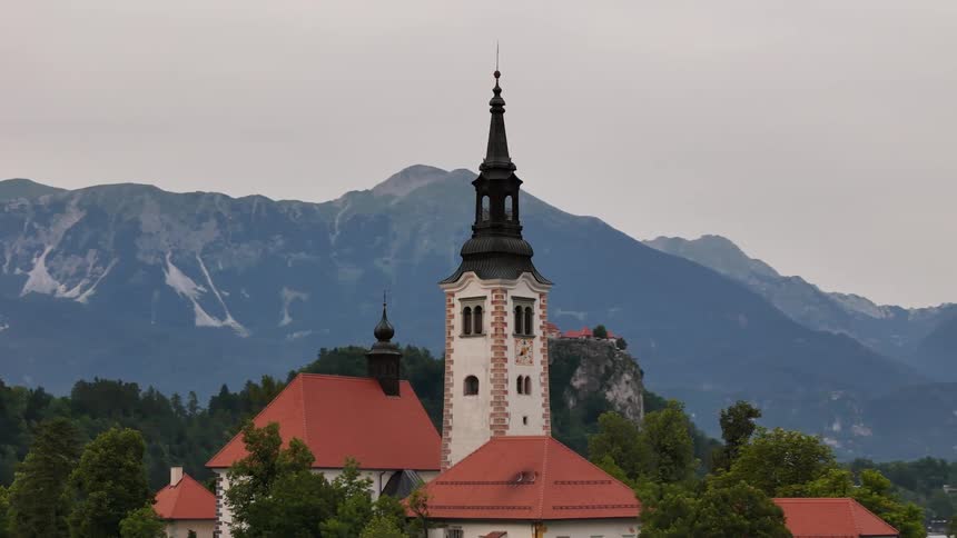 Tower reaches over the rooves of other buildings around in front of the mountains