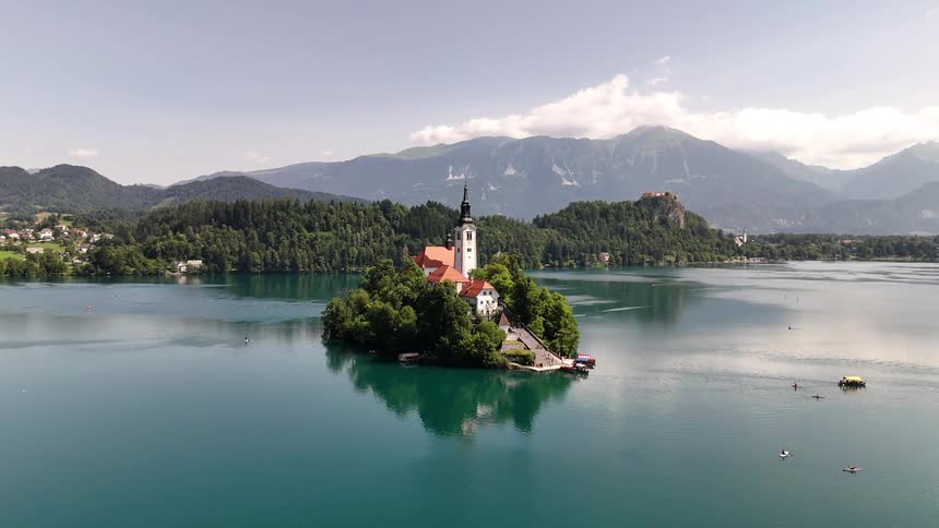 Aerial view of an island with a church in the center surrounded by a lake with turquoise water