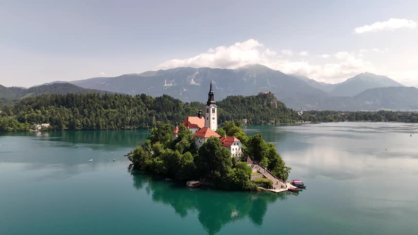 Castle on an island in the center of a lake in front of the mountains