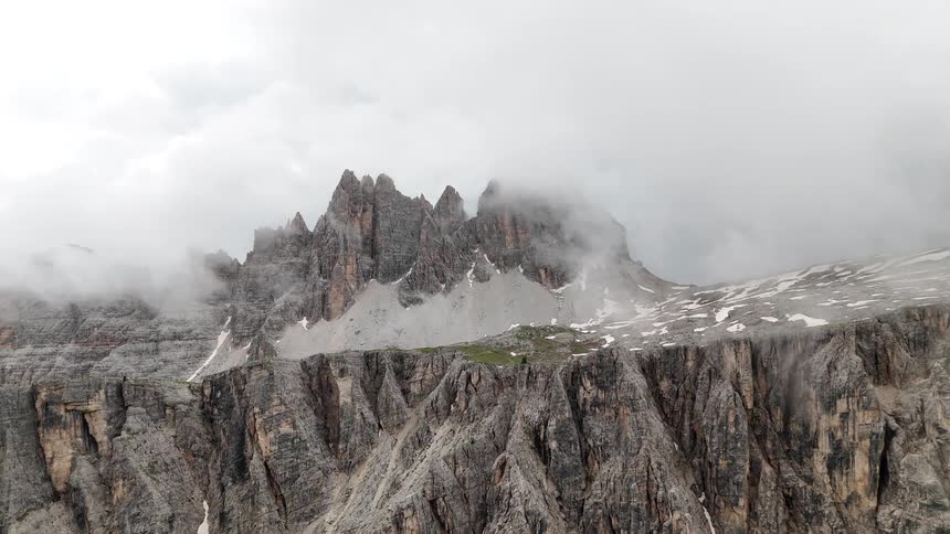 Panorama of rocky mountains with snow and fog
