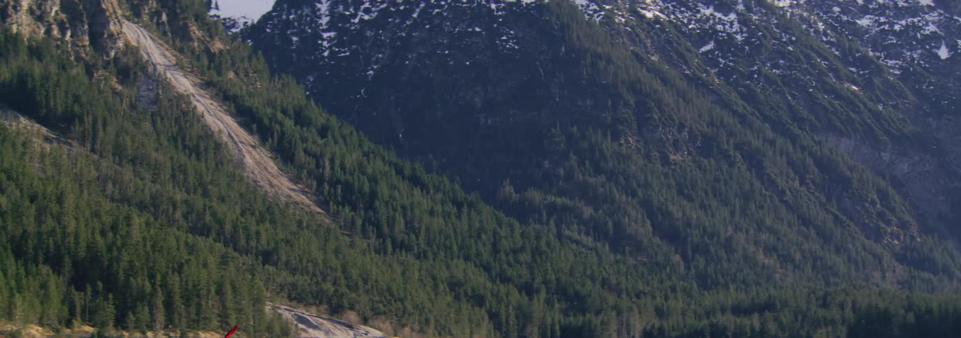 Person paddling a kayak while on a calm lake with mountains around