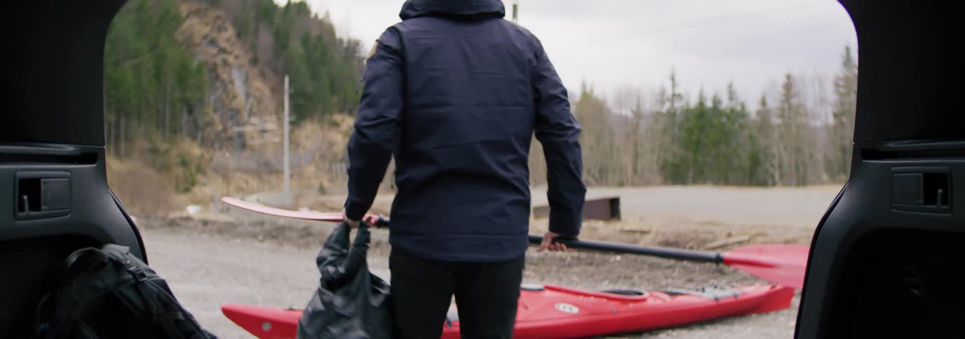 A man removes a kayak from the hatch of his vehicle