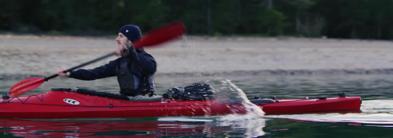 A man paddles a kayak across the water