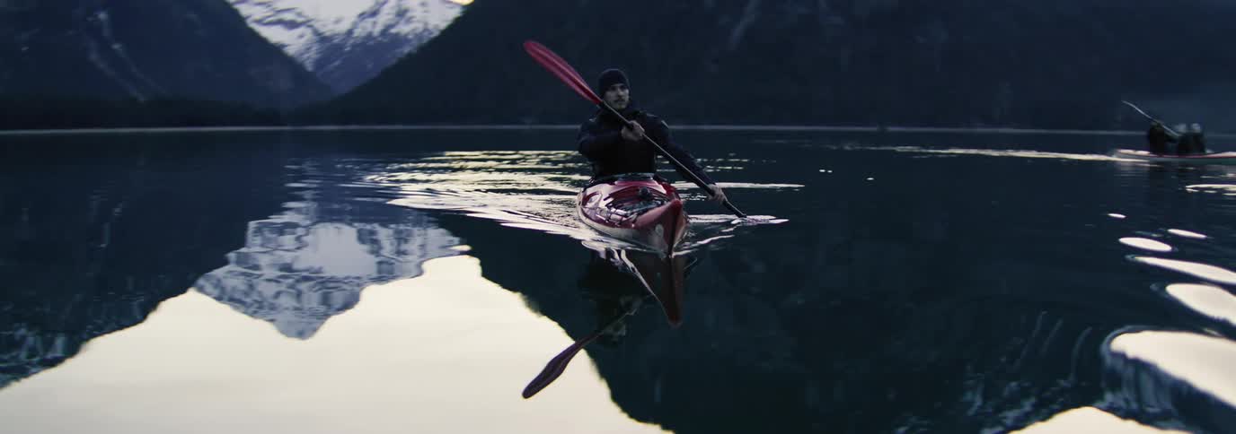 A man kayaks on the reflective water