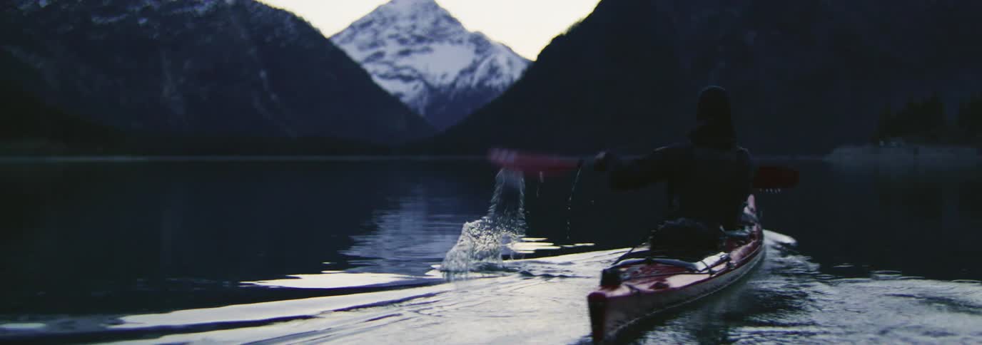 Man paddling a red kayak on a lake
