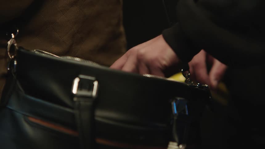 A thiefs hands take a notebook out of a purse