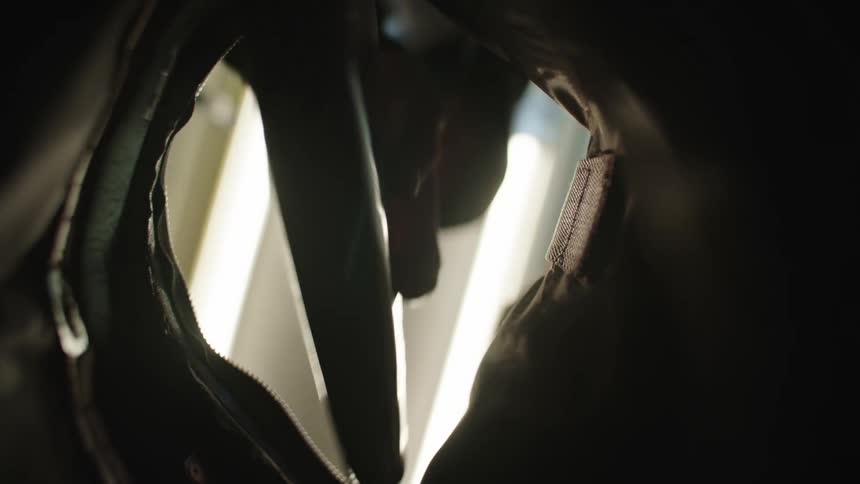 Person wearing a hoodie removes a smartphone from a purse