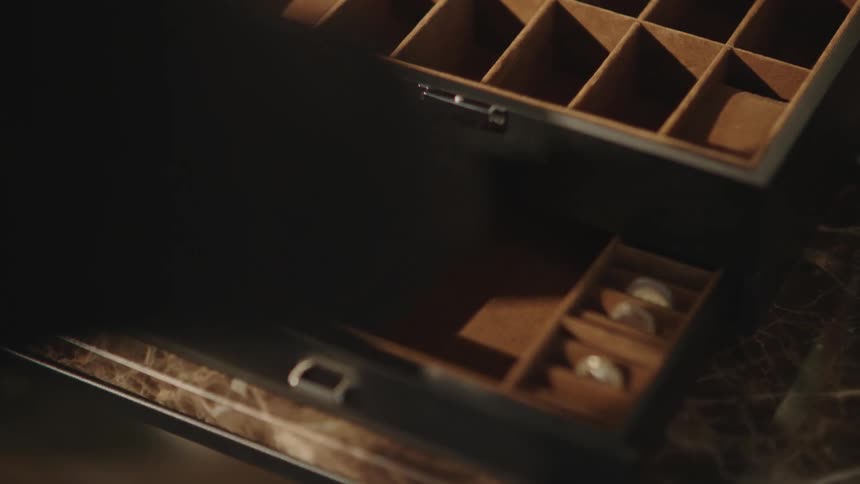 Pair of hands with black gloves stealing jewelry from a box