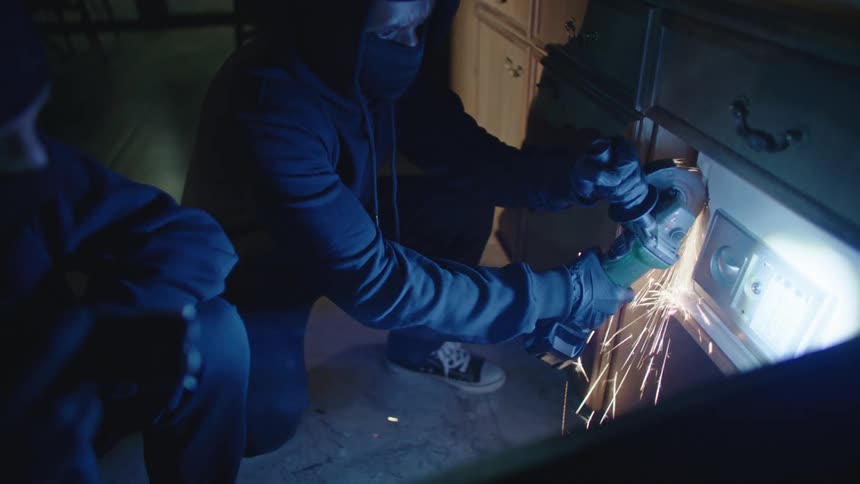 Two men are using a angle grinder to break into a safe
