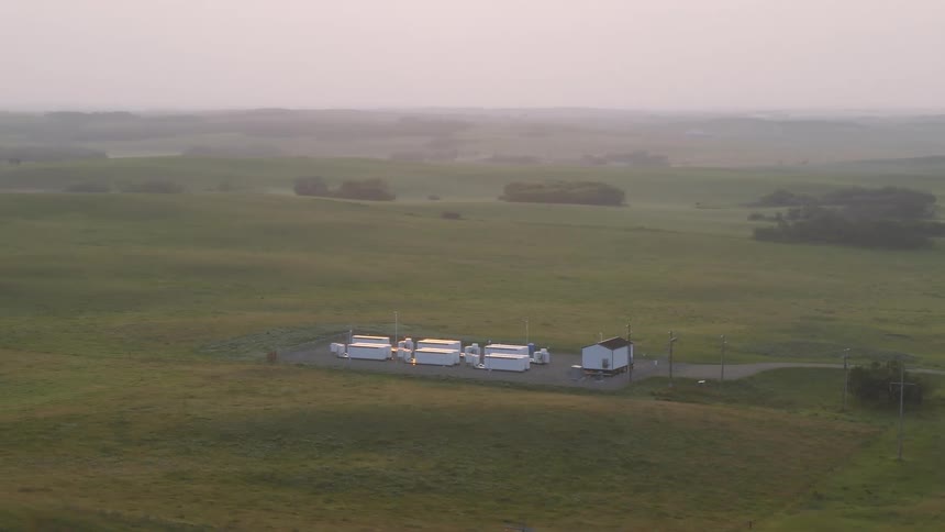The sun shines off battery cabinets in a field during summer