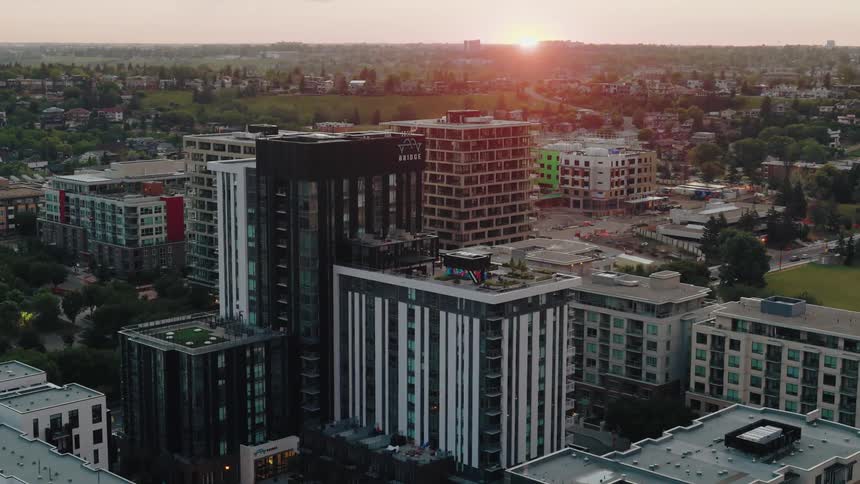 A cityscape at sunset with modern buildings and a park
