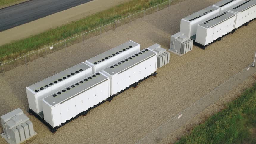 An aerial view of large industrial electrical units in rows on a gravel surface