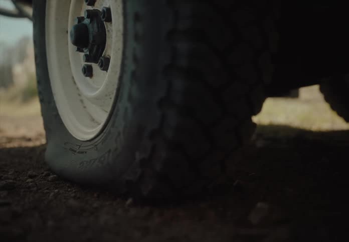 Vehicle with a flat tire stops on a dirt road