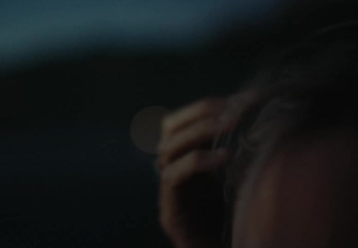 A woman brushes her hair as the wind blows it