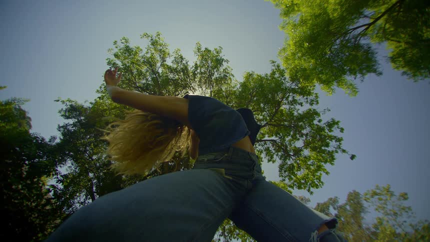 A young woman dances in slow motion on a midsummer day
