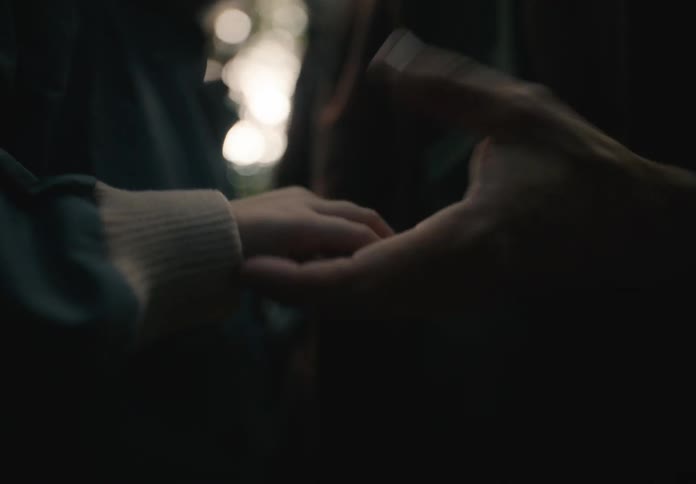 A pair of adult hands hold and caress a childs hands