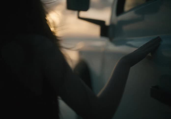 A little girl running her hand over the bodywork of a white car