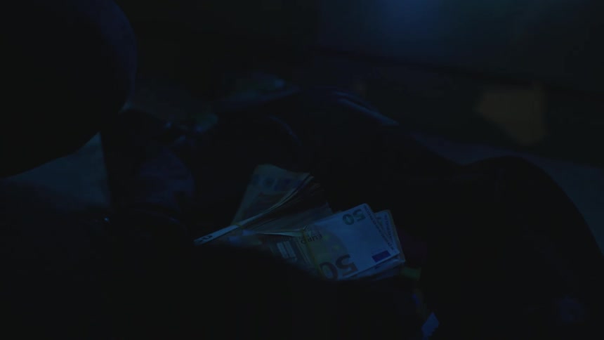 Thief stealing money from a safe in a dark room