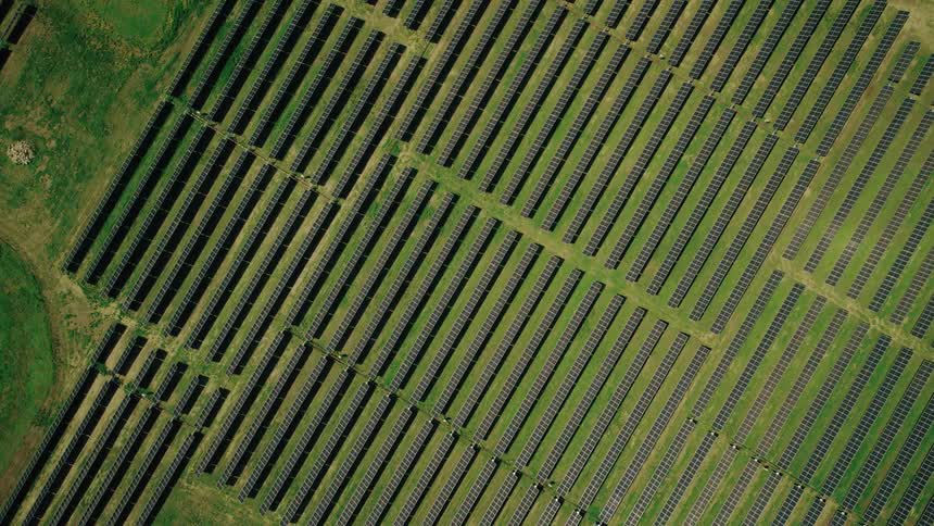 Aerial top-down view of a large solar farm on green grass