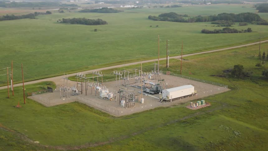 An aerial view of an electrical substation set in a vast green rural landscape