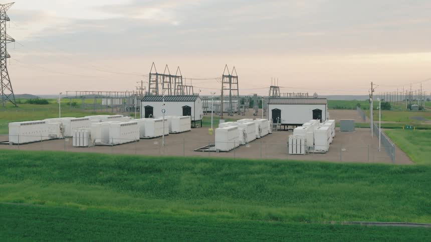 Slow aerial view of battery backup units on a grassy plain