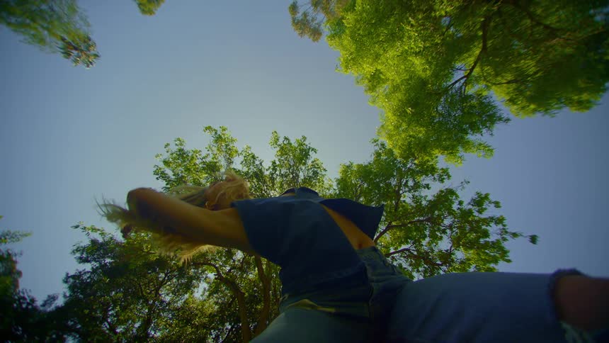 Woman dancing under the trees on a clear day