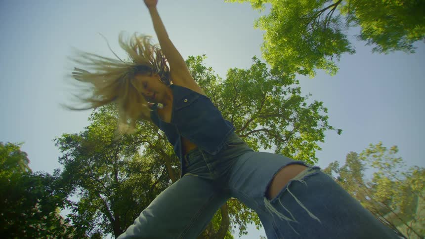 Blonde woman in a place with trees around dancing