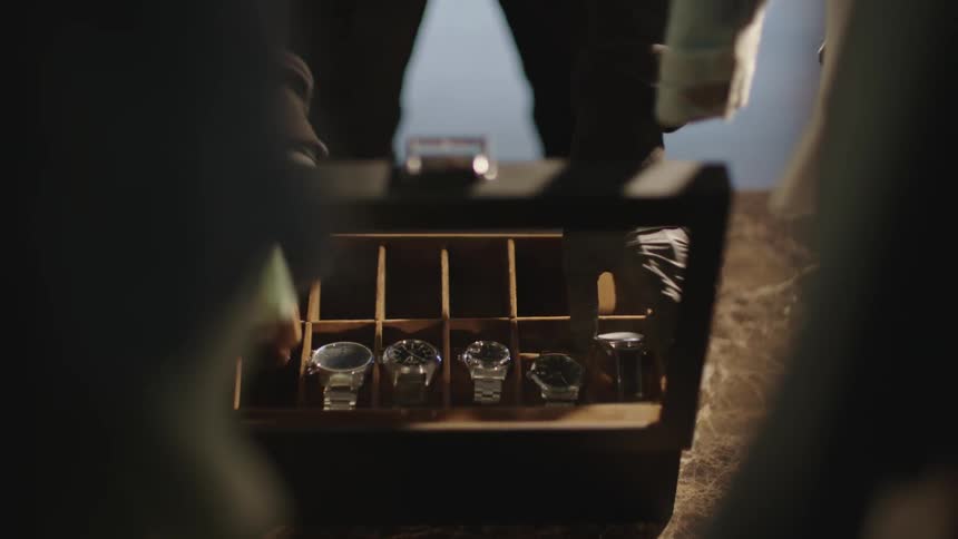 A thief wearing a balaclava opens a bedroom closet and a box inside and takes all the wristwatches in the box