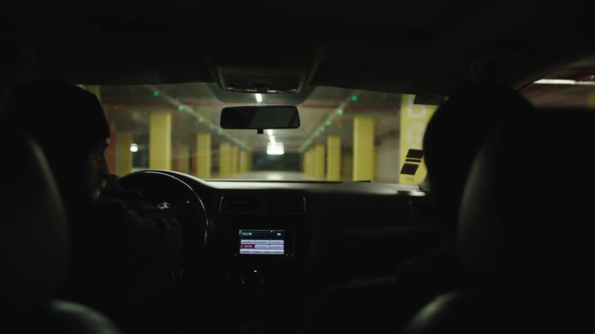 A view from inside a car driving through an underground parking garage with yellow pillars