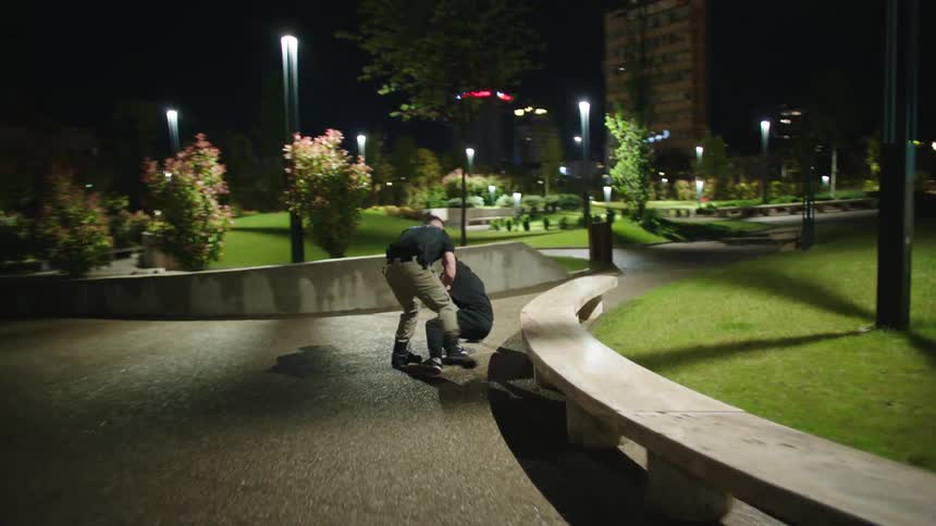 Two policemen chase down and apprehend a criminal in the area between office buildings at night