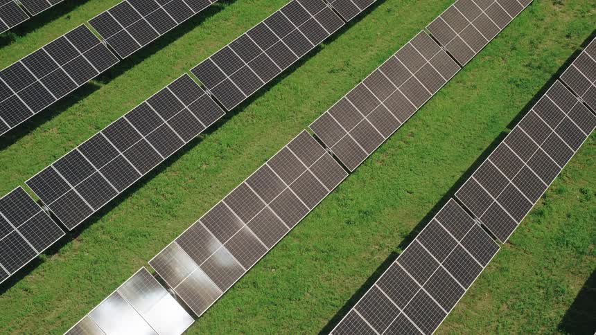 Rows of solar panels shining in a grassy field