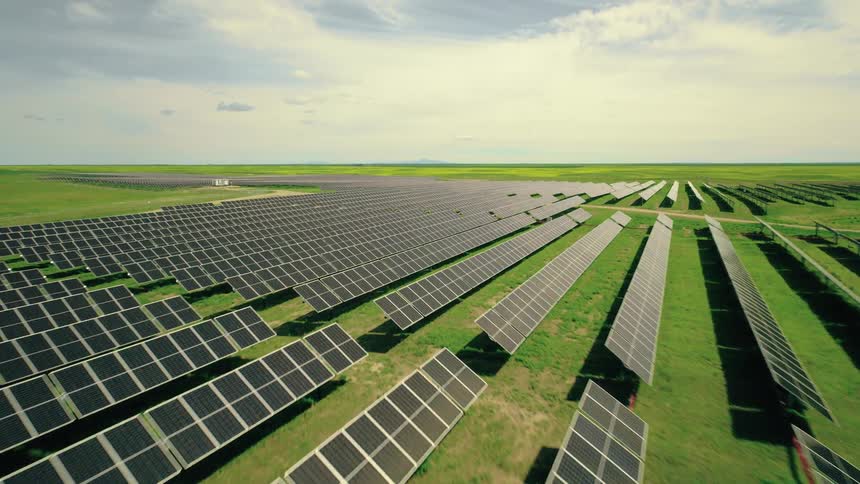 A dynamic aerial view of a solar farm with rows of photovoltaic panels