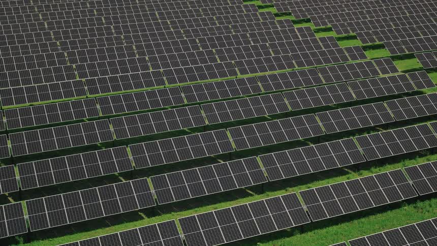Gently moving aerial view of an solar farm with large rows of panels