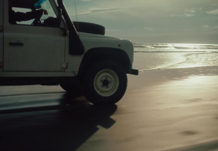 An atv driving on a beach along the water line