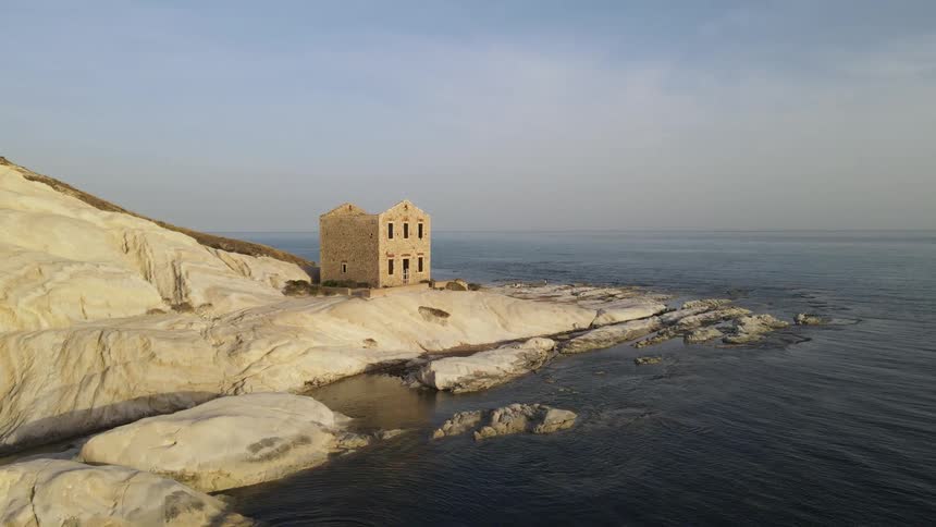 An ancient stone building situated on a scenic rocky coastline overlooking the ocean