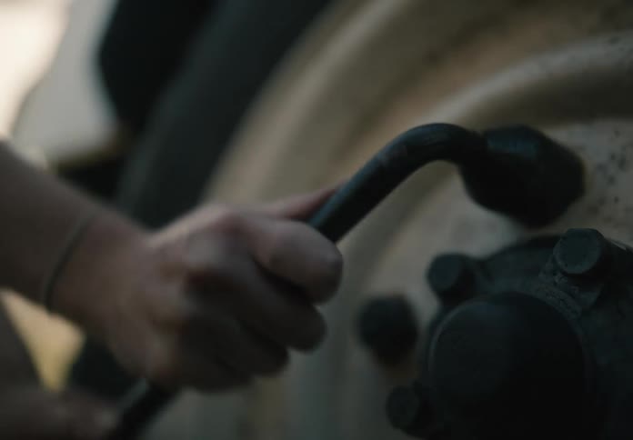 A persons hands as they use a tyre iron to tighten the tyres bolts
