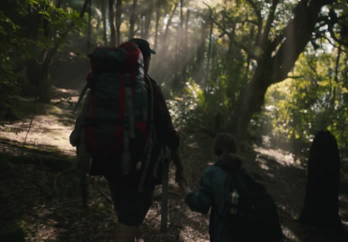Father and daughter step over a log during their hike in the forest
