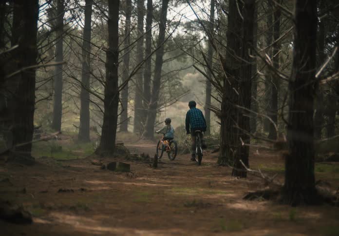 Father and child pedaling a bicycle in a forest
