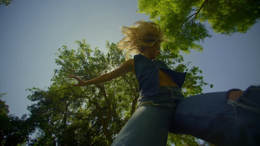 Blondehaired woman dancing in a park with trees