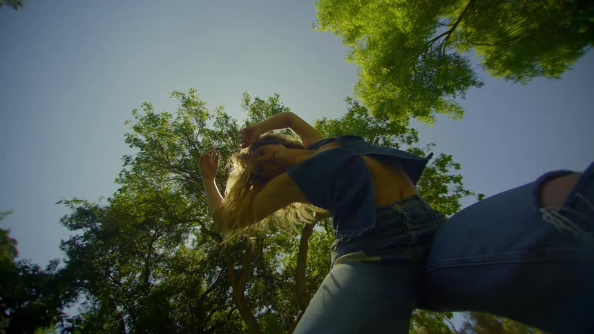 A woman dancing between the trees in her backyard