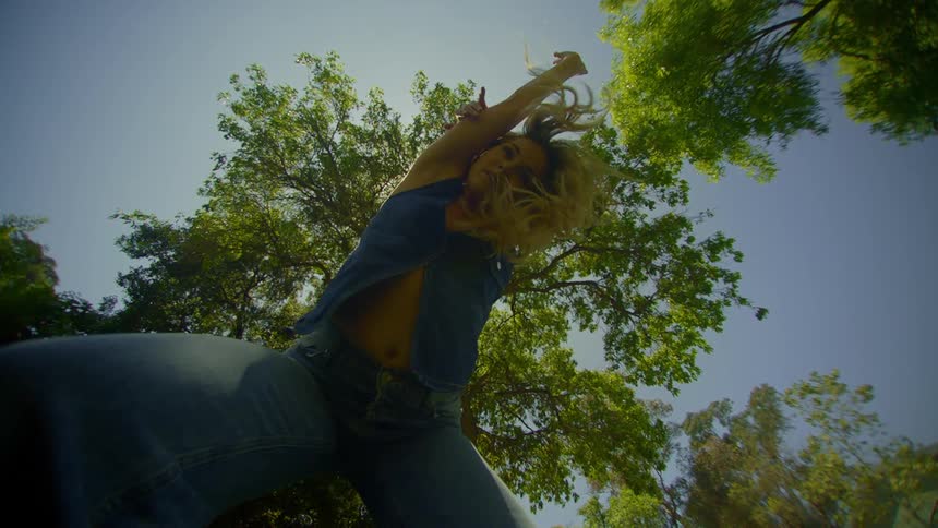 A lowangle view of a person standing against a sunny sky with trees in the background