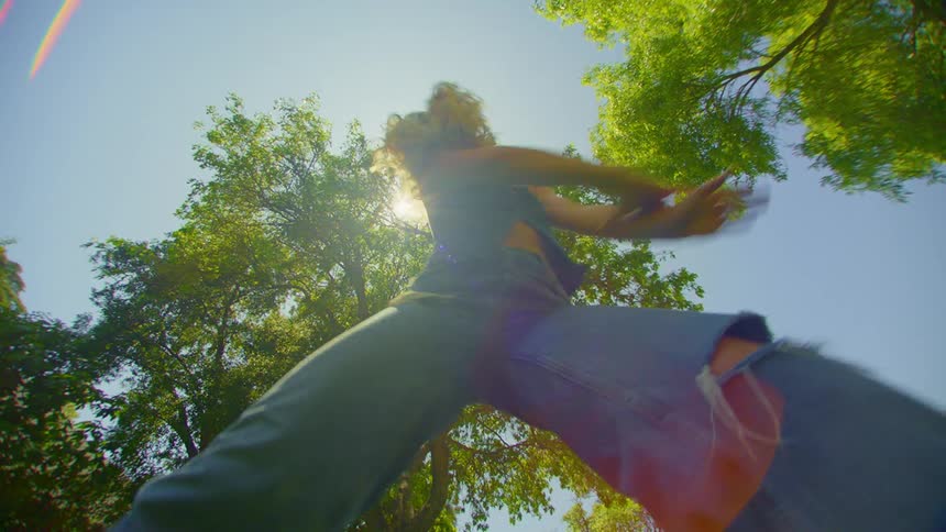A woman dances in a park in the summer under a clear blue sky