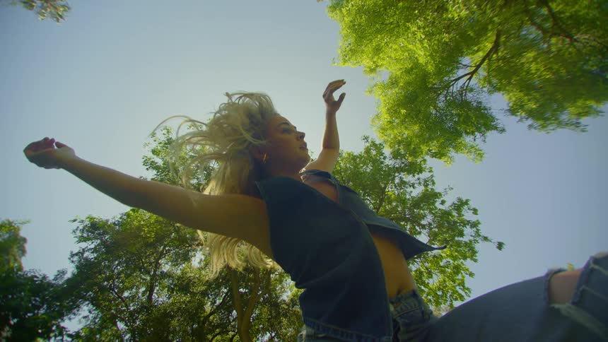 Blonde woman dances in a grove on a sunny summer day