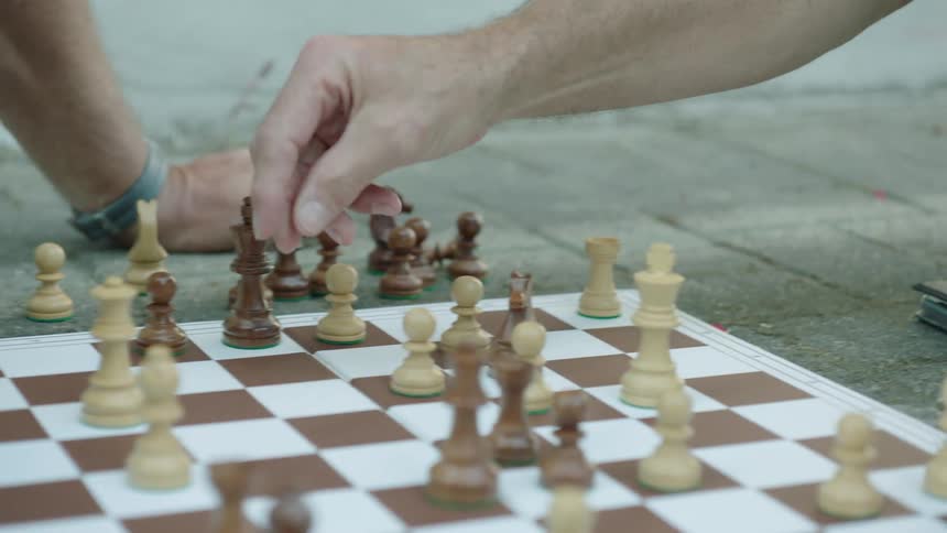A closeup of hands moving pieces on a chessboard