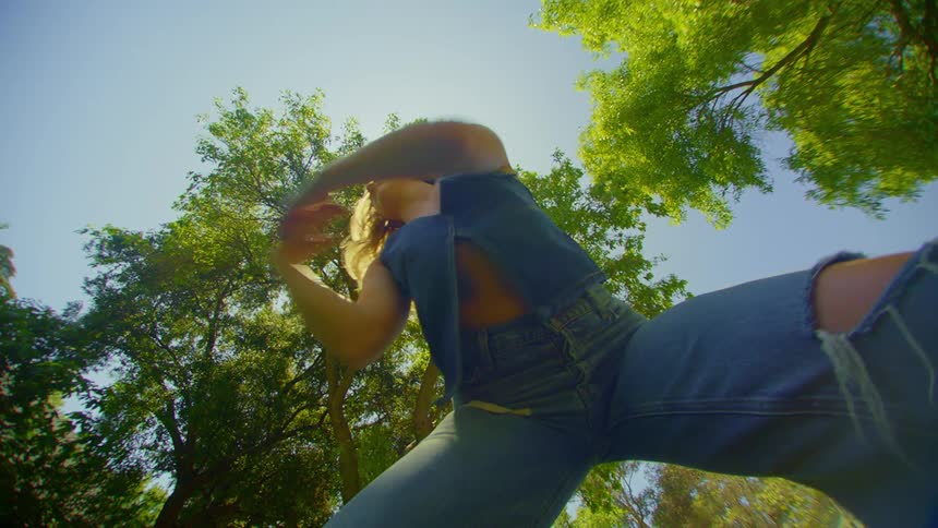 A lowangle view of a person standing against a sunny sky with trees in the background
